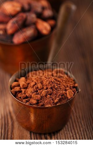 cocoa powder and grated chocolate  in vintage measuring copper pans  on old wooden background