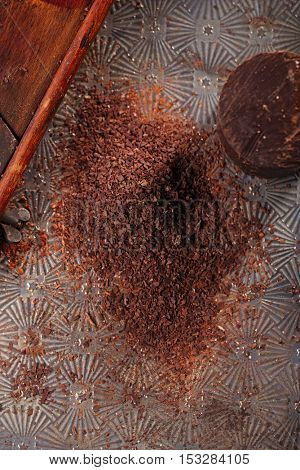 grated 100% dark chocolate flakes on vintage  wooden grate,   shallow DOF