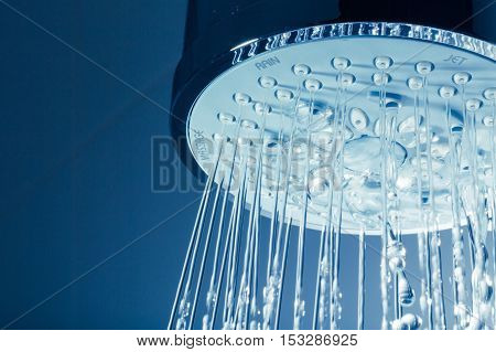 Shower Head with Water Stream on Blue Background