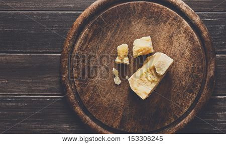 Cheese delikatessen on rustic wood. Wooden desk with parmesan cuts, top view image with copy space