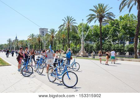 Barcelona, Spain - May 27, 2016: tourist group on bicycles on pedestrian alley in front of the Arc de Triomphe