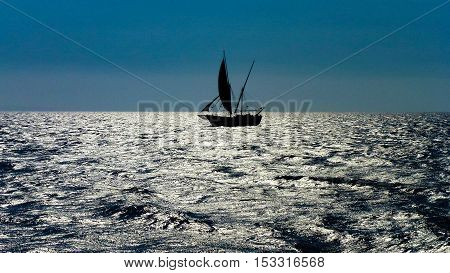 Sailer floating on the silver ocean surface