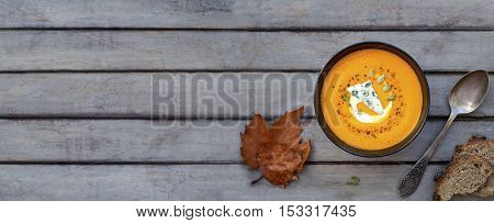Hot pumpkin soup with blue cheese, herbs and multi-cereal bread on a wooden table. View from above