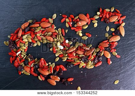 Nut mix snack with raisins, pumpkin seeds, almonds and goji berries on stone board.