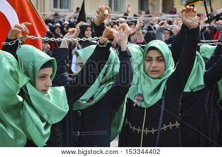 Istanbul Turkey - October 11 2016: Shiite Muslim women hold up their chained hands as they mourn during an Ashura procession. Turkish Shia Muslims mourning for Imam Hussain. Caferis take part in a mourning procession marking the day of Ashura in Istanbul'