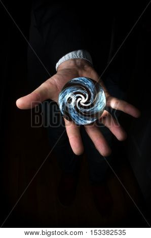 Hands holding magic crystal ball with smoky hypnosis spiral