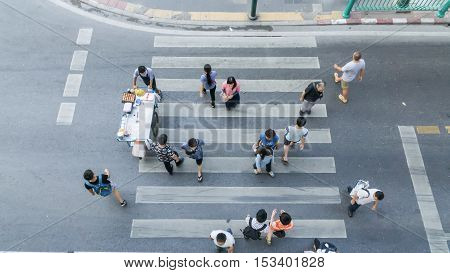 Top view of people are moving across the pedestrian crosswalk in the city street (Aerial photo)
