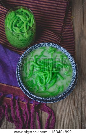 Lod Chong, Thai Dessert on Thai Textile with Wood Background Rice Noodles Made of Rice Eaten with Coconut Cream