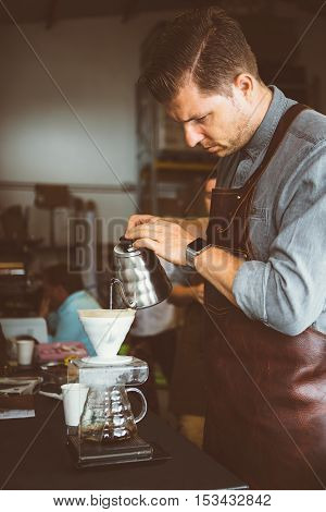 Portrait of professional coffeemaker pouring hot water in coffee machine