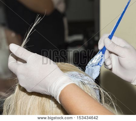 Hairdresser is hair dying some blonde hair.