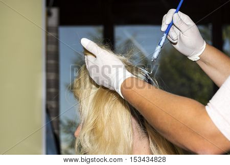 Hairdresser is hair dying some blonde hair.
