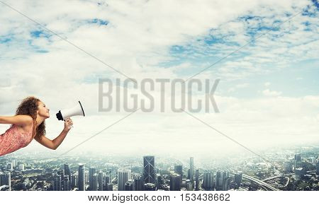 Young woman in dress making announcement in megaphone