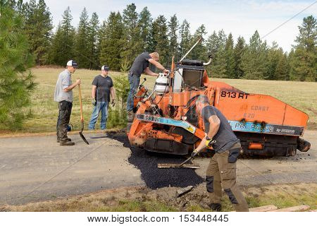 Colbert, WA - October 24, 2016: Workers of Black Diamond Asphalt Paving, LLC., repairing patches in a private road/driveway