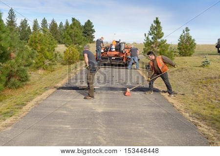 Colbert, WA - October 24, 2016: Workers from Black Diamond Asphalt Paving, LLC., repairing patches and re-paving a private road/driveway