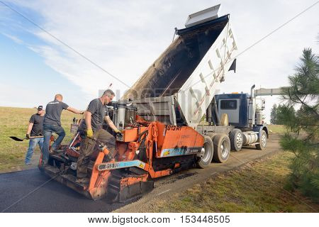 Colbert, WA - October 24, 2016: Workers from Black Diamond Asphalt Paving, LLC., repairing patches and re-paving a private road/driveway