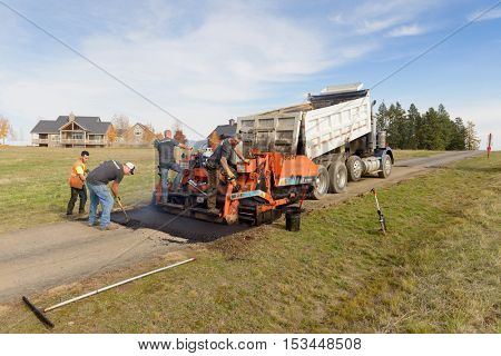 Colbert, WA - October 24, 2016: Workers from Black Diamond Asphalt Paving, LLC., repairing patches and re-paving a private road/driveway
