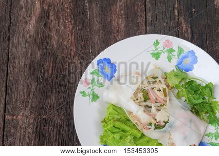Closeup Fresh Spring Roll with vegetable and coriander in plateThailand food on the wooden table top view