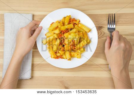 Baked tortiglioni pasta with tomato sauce mozarella and parmesan cheese in plate on wooden table