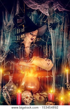 Attractive witch conjures in the wizarding lair. Fairytales. Halloween.