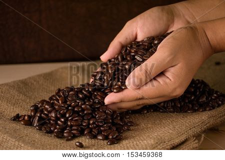 Coffee beans in hands hemp sack on wood table