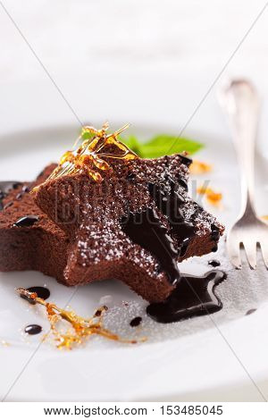 Homemade tasty delicious christmas dessert on a plate - brownie with caramel and chocolate sauce selective focus