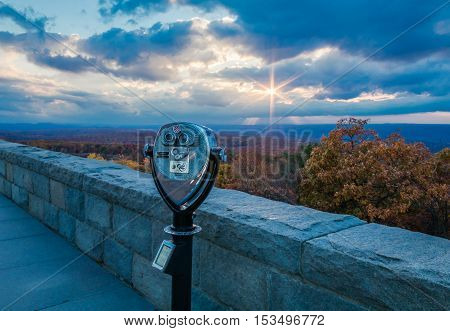 Binoculars point towards a majestic sunburst overlooking brilliant fall foliage at the top of New Jersey at High Point State Park