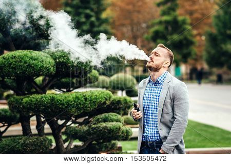 Men With Beard Smoking Electronic Cigarette Outdoor