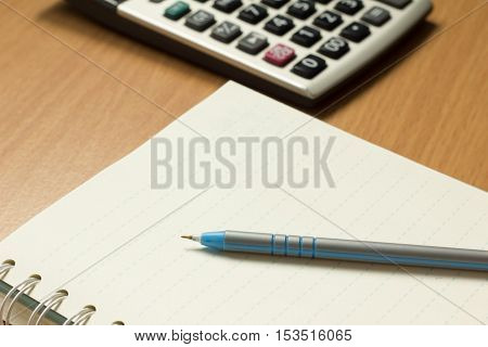 Pen placed on the book with calculator background
