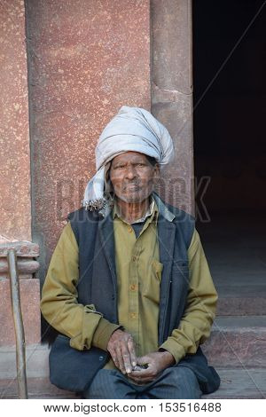 AGRA, UTTAR PRADESH, INDIA - FEBRUARY 04, 2016 - Unidentified aged indian man sitting outside Red Fort
