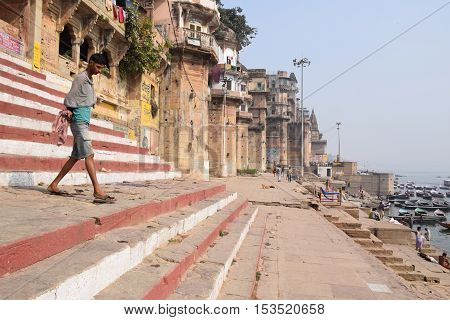VARANASI, UTTAR PRADESH, INDIA - FEBRUARY 17, 2016 - Unidentified indian guy going down the steps of the ghats towards the holy river Ganga