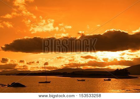 boats in a quiet bay with island near kenmare on the wild atlantic way ireland with an orange sunset