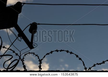 silhouette of a birbed wire and a wire