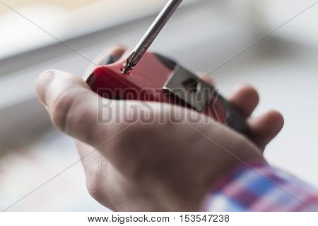 the young man unscrews the screw with a screwdriver