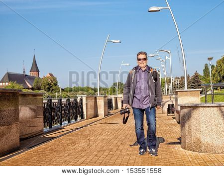 elderly man walking with a camera on the waterfront on sunner