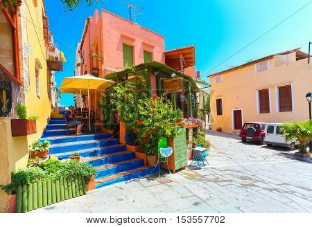 Rethymnon, Island Crete, Greece - July 1 2016: Cozy Cretan small cafe with flowers outside with ad on the green board about Cretan cuisine