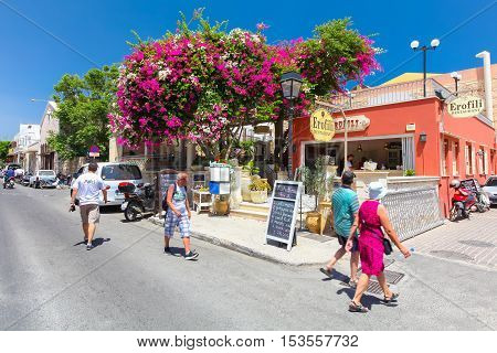 Rethymnon, Island Crete, Greece - July 1 2016: People and tourists walking on the street of Rethymnon near the cozy Cretan cafe with ad on the black board 