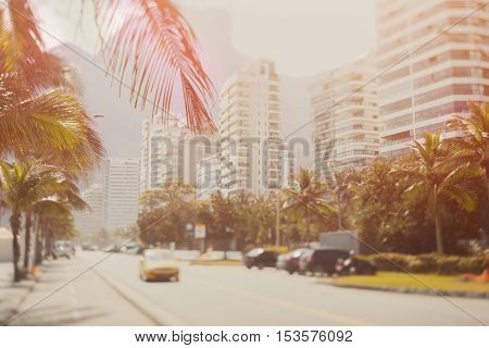 Tilt shift shooting of road in Rio de Janeiro on a sunny summer day taxi on the road palms residential houses far mountains