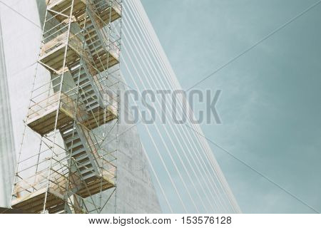 Rope bridge under construction with regular metal ropes and scaffolding on a sunny summer day in Rio de Janeiro with clear sky above view from bottom