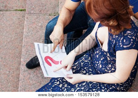 Pregnant couple plans a date of baby birth with the calendar. Maternity concept. Expecting an upcoming baby. Due date countdown. Top view.