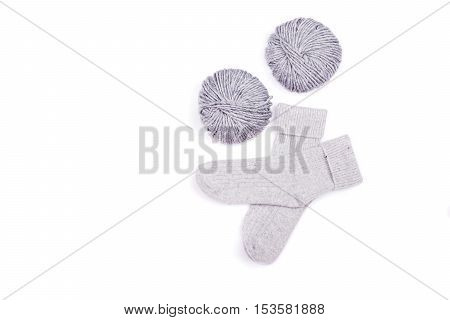 Pair of gray woolen socks and two knitting yarns isolated on white background