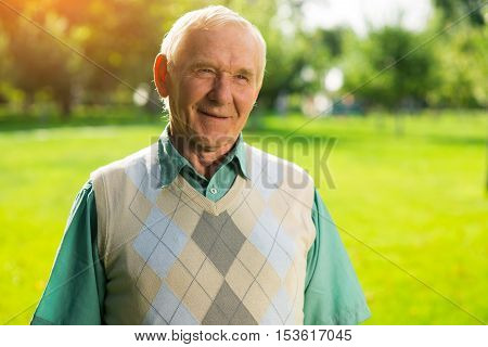 Senior man is smiling. Elderly male on nature background. Veteran of labor. Wise mind and modest smile.