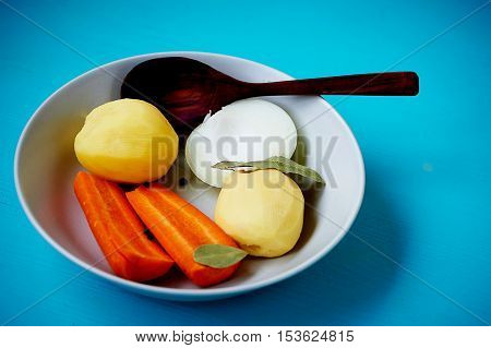 Poseshenie vegetables to prepare vegetable soup with spices on a light plate . Blue background