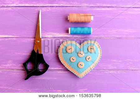 How to create a felt heart crafts. Step. Decorative felt heart with buttons, scissors, thread set, needle on wooden background. Sewing crafts for Valentine's day, wedding, mother's day