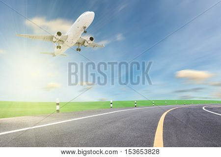 Airplane take off with road curve and beautiful green grass blue sky scenery background open high season travel and tour concept