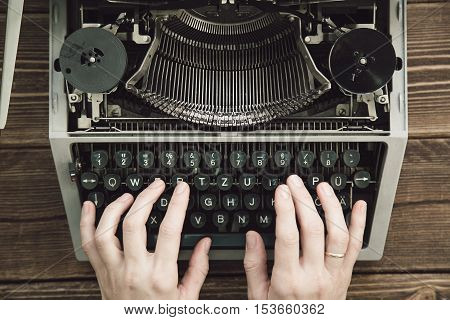 Writer typing with retro writing machine. View from above.