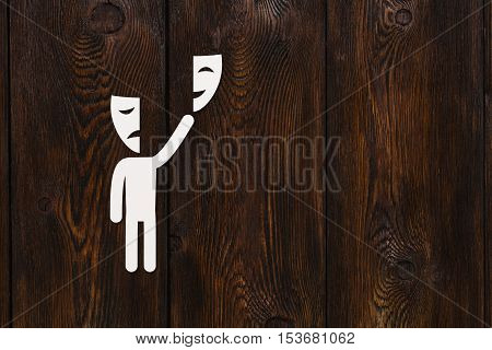 Paper man with theatre masks. Choice or emotions concept. Abstract conceptual image with copyspace. Dark wooden background