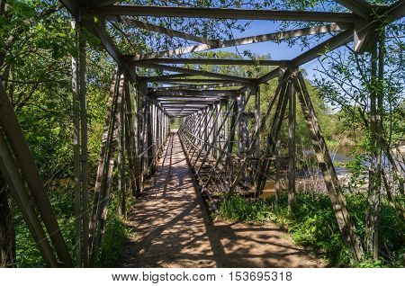 The old rural pedestrian openwork metal bridge not far from TarusaRussia