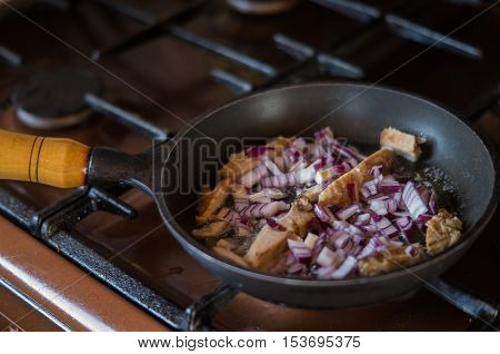 Some onion and bacon in a frying pan while cooking Breakfast.