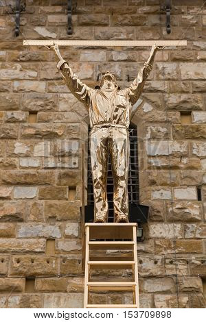 FLORENCE, ITALY - SEPTEMBER 2016 : Shiny bronze sculpture statue of The Man Who Measures the Clouds, man standing atop ladder with ruler in Florence, Italy on September 21, 2016. By Jan Fabre