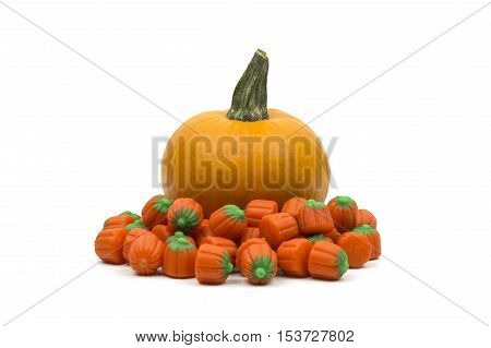 Small pumpkin surrounded by candies isolated on white